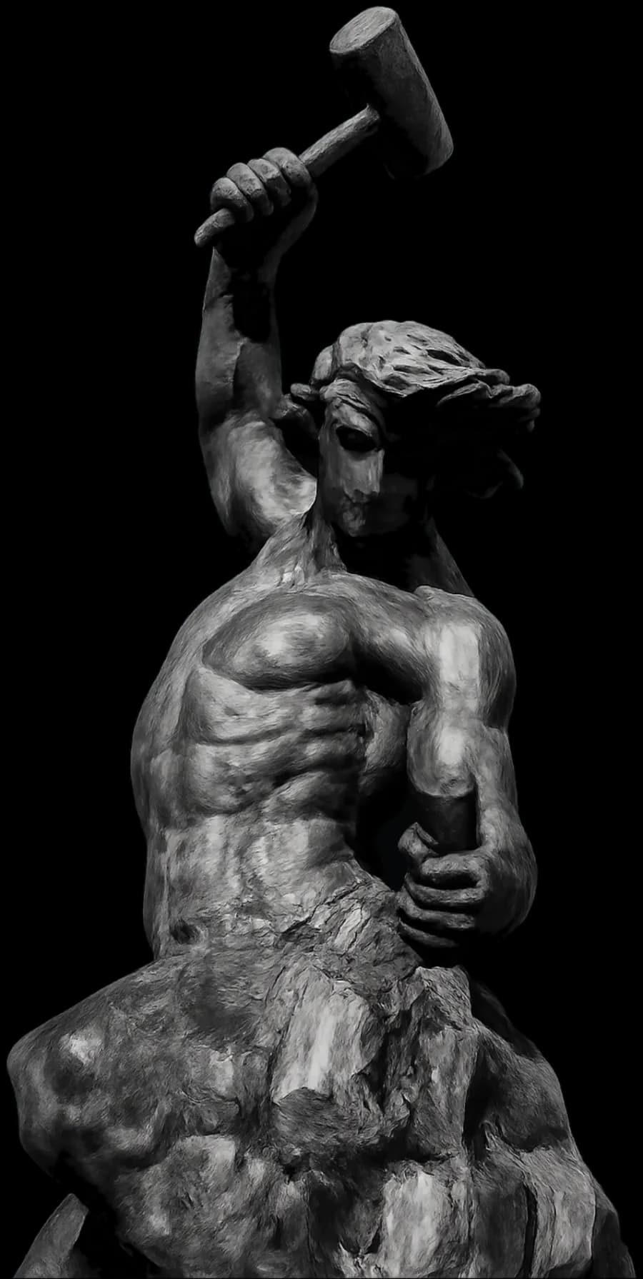 Statue of a man carving himself from stone, hammer raised